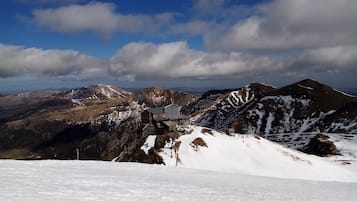 A mountain lodge with a snow-covered peak, a clear sky, and distant mountains.