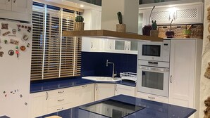 A modern kitchen with white cabinets, a blue countertop, and stainless steel appliances.