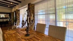 A dining area with a wooden table, woven placemats, wicker chairs, and a candelabra centerpiece.