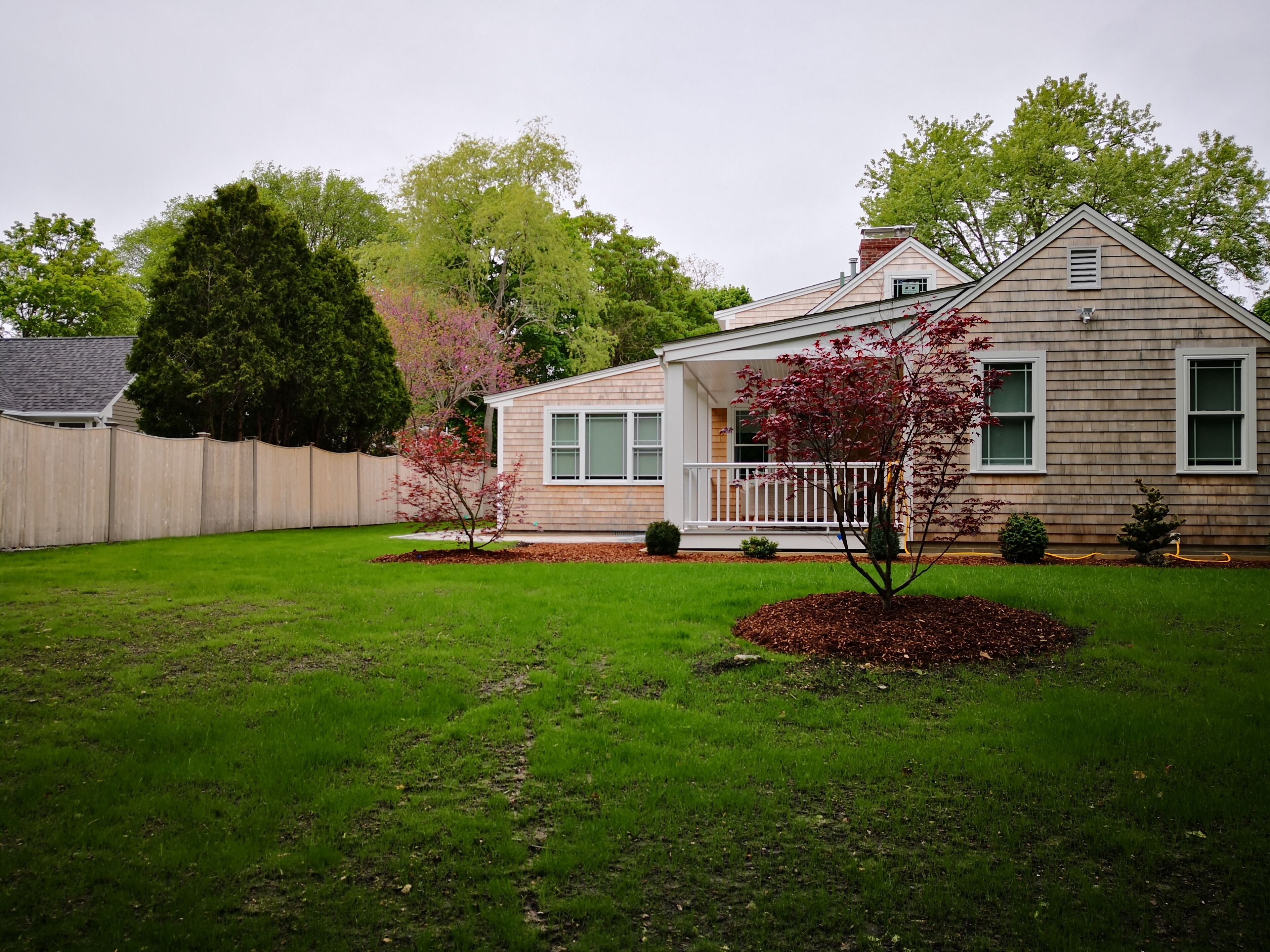 A single-story house with a front porch, a fenced backyard, and a well-maintained lawn.