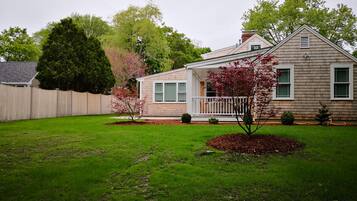 A single-story house with a front porch, a fenced backyard, and a well-maintained lawn.