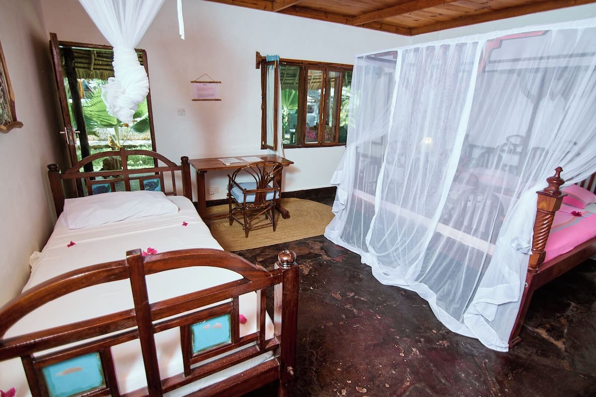 Una habitación con una cama, un escritorio y una silla. Hay una ventana con cortina.