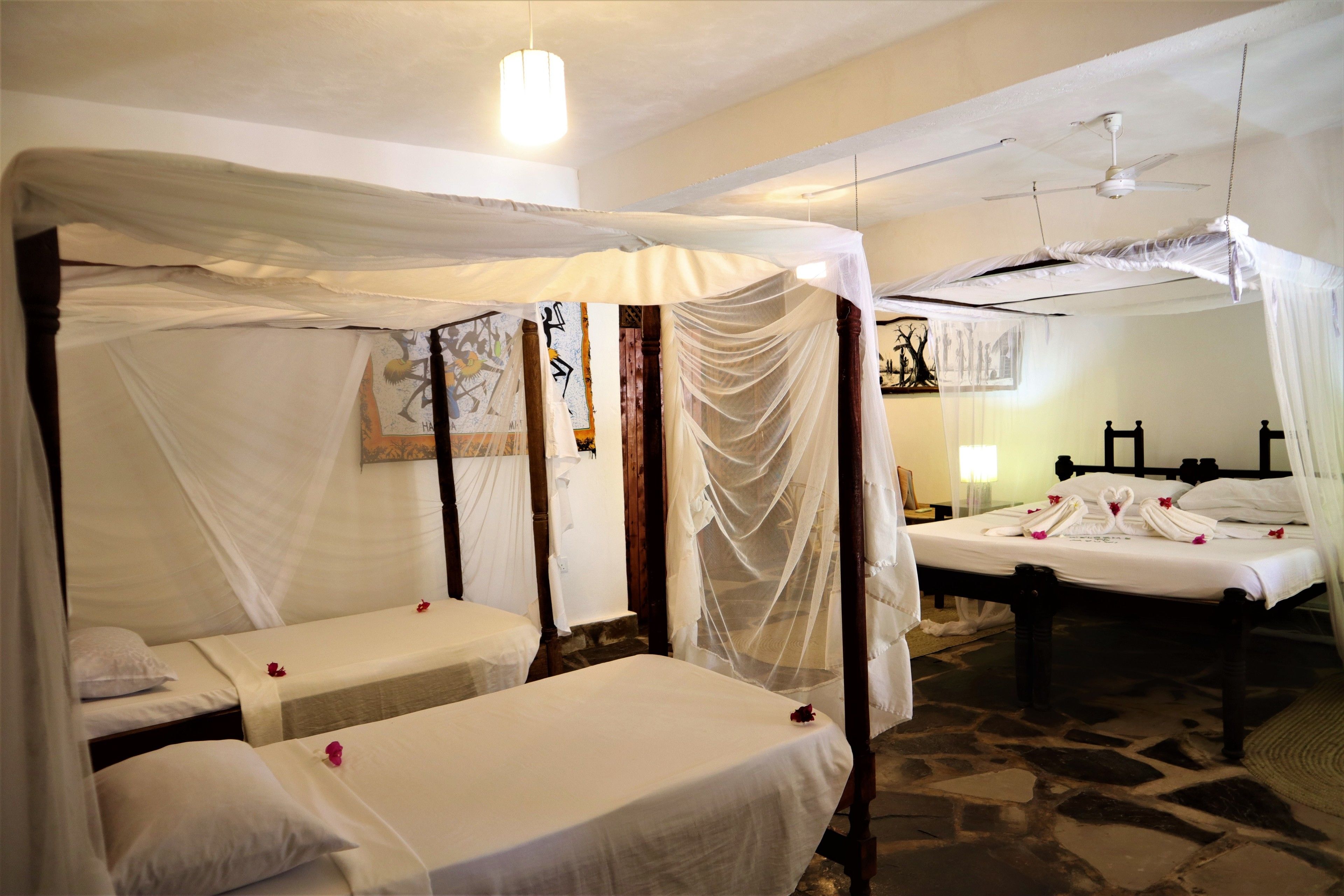 Une chambre avec deux lits, chacun recouvert de draps blancs et surmonté d’un dais blanc.