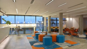 Un hall espacioso con ventanas amplias, zonas de estar y un mostrador de recepción.