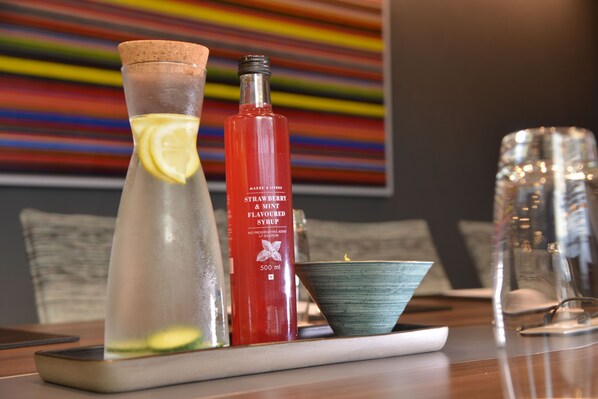 A table with a glass pitcher, a bottle of strawberry & mint flavored syrup, and a bowl. - Town Lodge Umhlanga (Umhlanga)