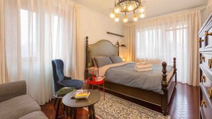 Ett hotellrum med en säng, en stol, ett litet bord, en kristallkrona och en byrå.