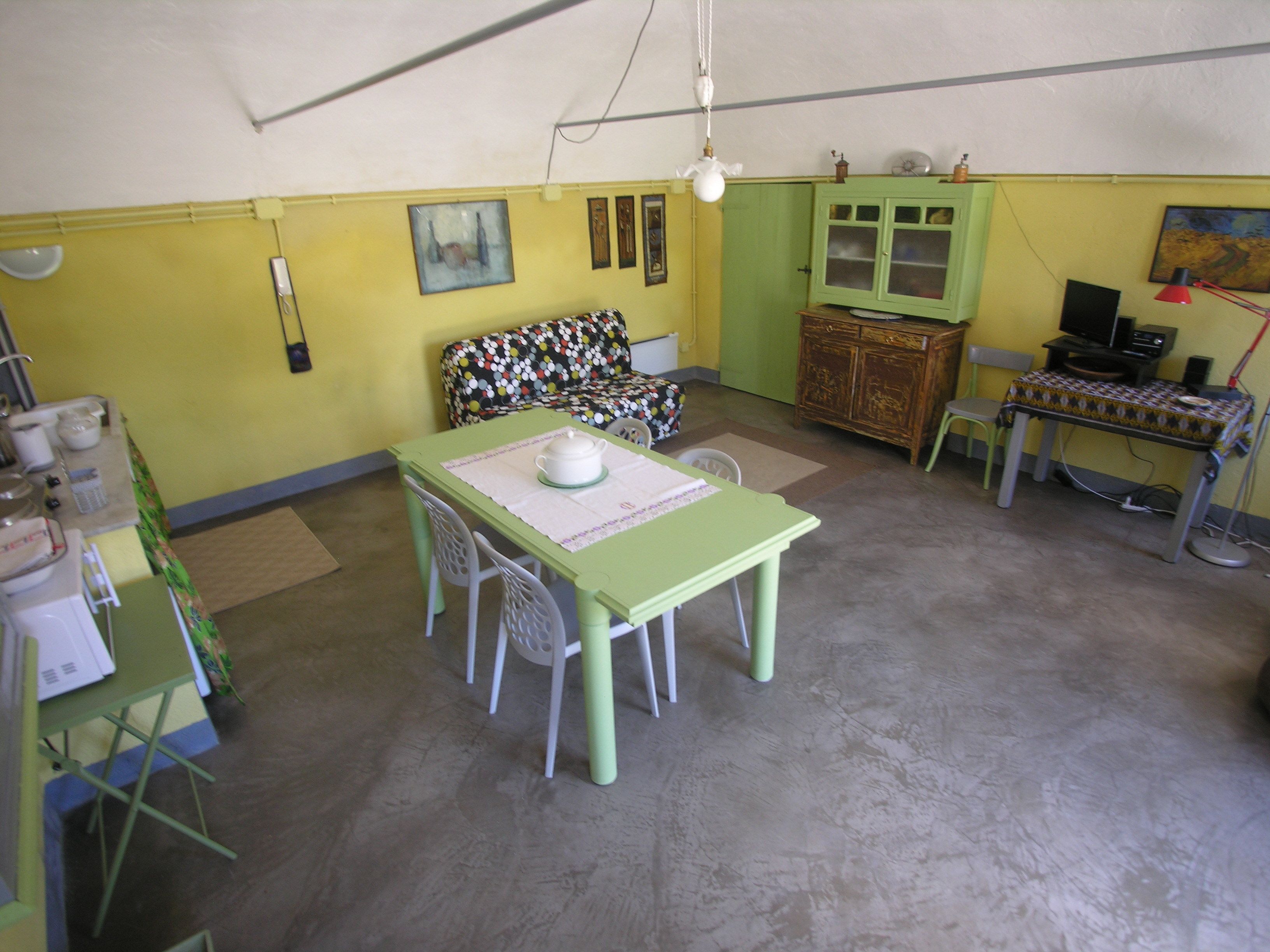 A small, cozy room with a green table and chairs, a yellow wall, and a green cabinet.