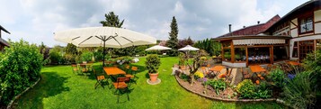 Un jardín cuidado con zona de estar al aire libre y espacio cubierto.