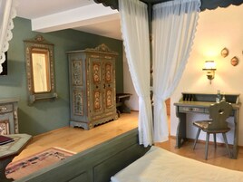 Un dormitorio con cama, escritorio, silla, armario y espejo.