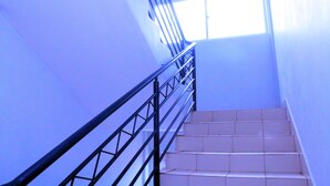 A staircase with a metal railing leading to a landing with a window. - Amelia Hotel Karen (Nairobi)