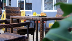 Wicker chairs and a table with a plate of food. - Amelia Hotel Karen (Nairobi)