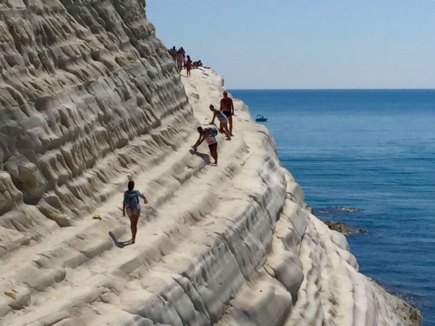 A coastal cliff with people walking along its edge.
