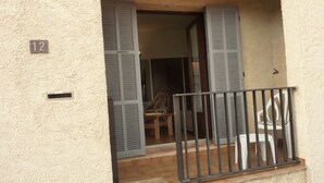 A building entrance with a number '12' sign, a wooden chair, and a metal railing. - Studio for rent in LUMIO in BALAGNE (Lumio)