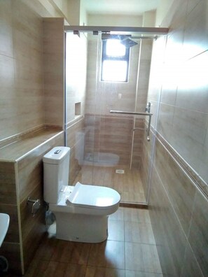 A bathroom with a toilet, a shower enclosure, and a window. - Scenic View Thindigua Apartments (Nairobi)
