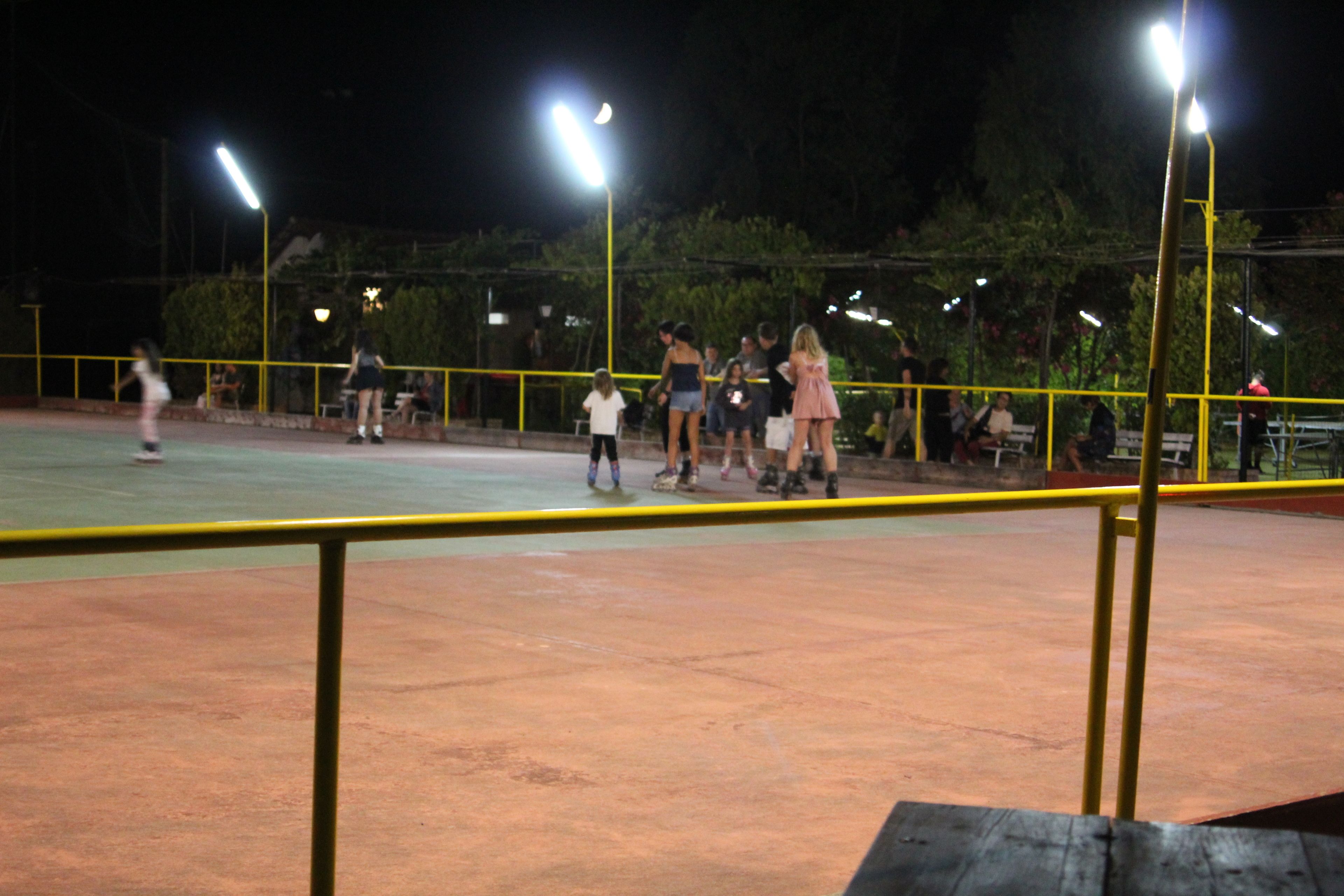 An outdoor tennis court at night with spectators.
