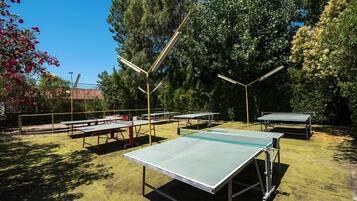An outdoor table tennis facility with multiple tables and overhead lighting.