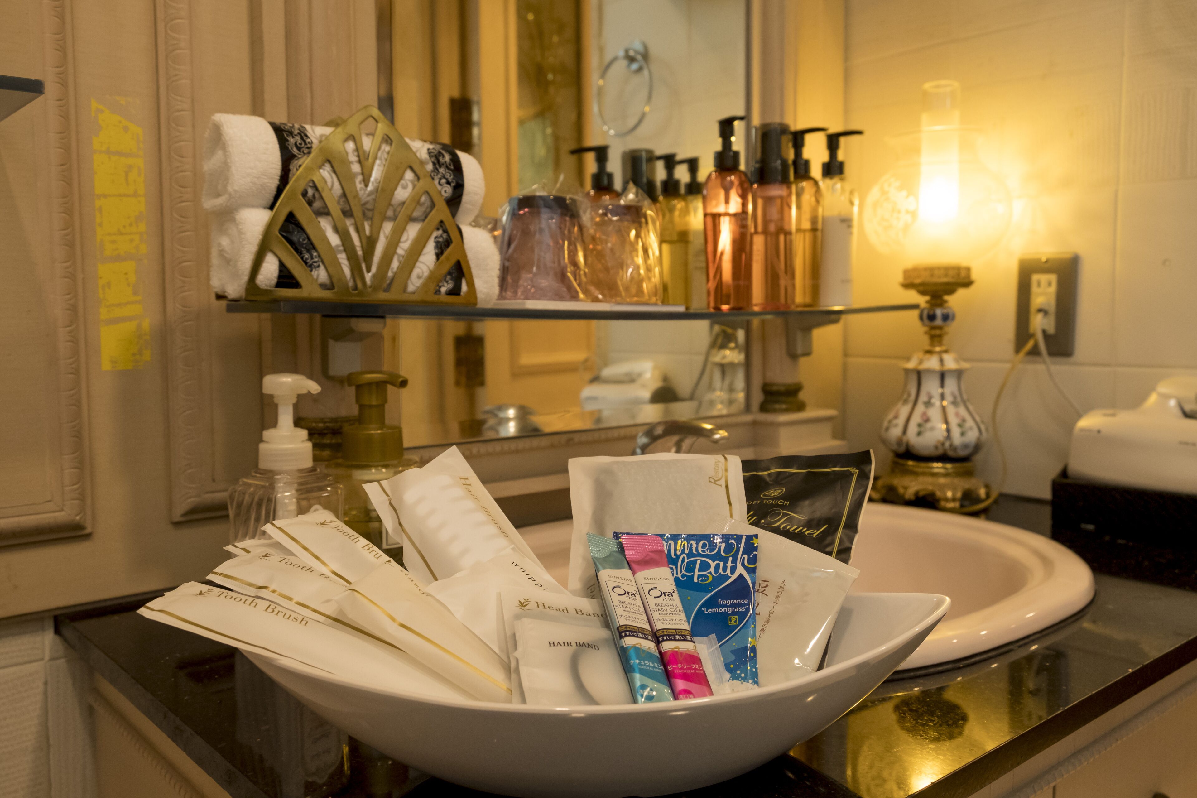 A hotel bathroom with a sink, toiletries, and a mirror.