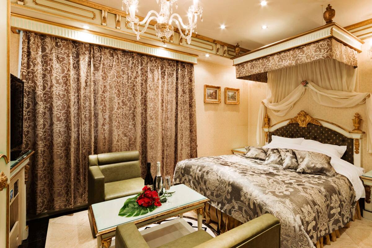 A luxurious bedroom with a large bed, a sitting area with a table, and a television.