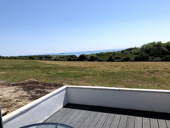 Una terraza en la azotea con vistas a un campo verde y al mar.