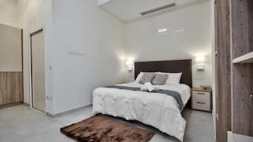 A modern bedroom with a large bed, bedside lamps, a nightstand, and a fluffy rug.