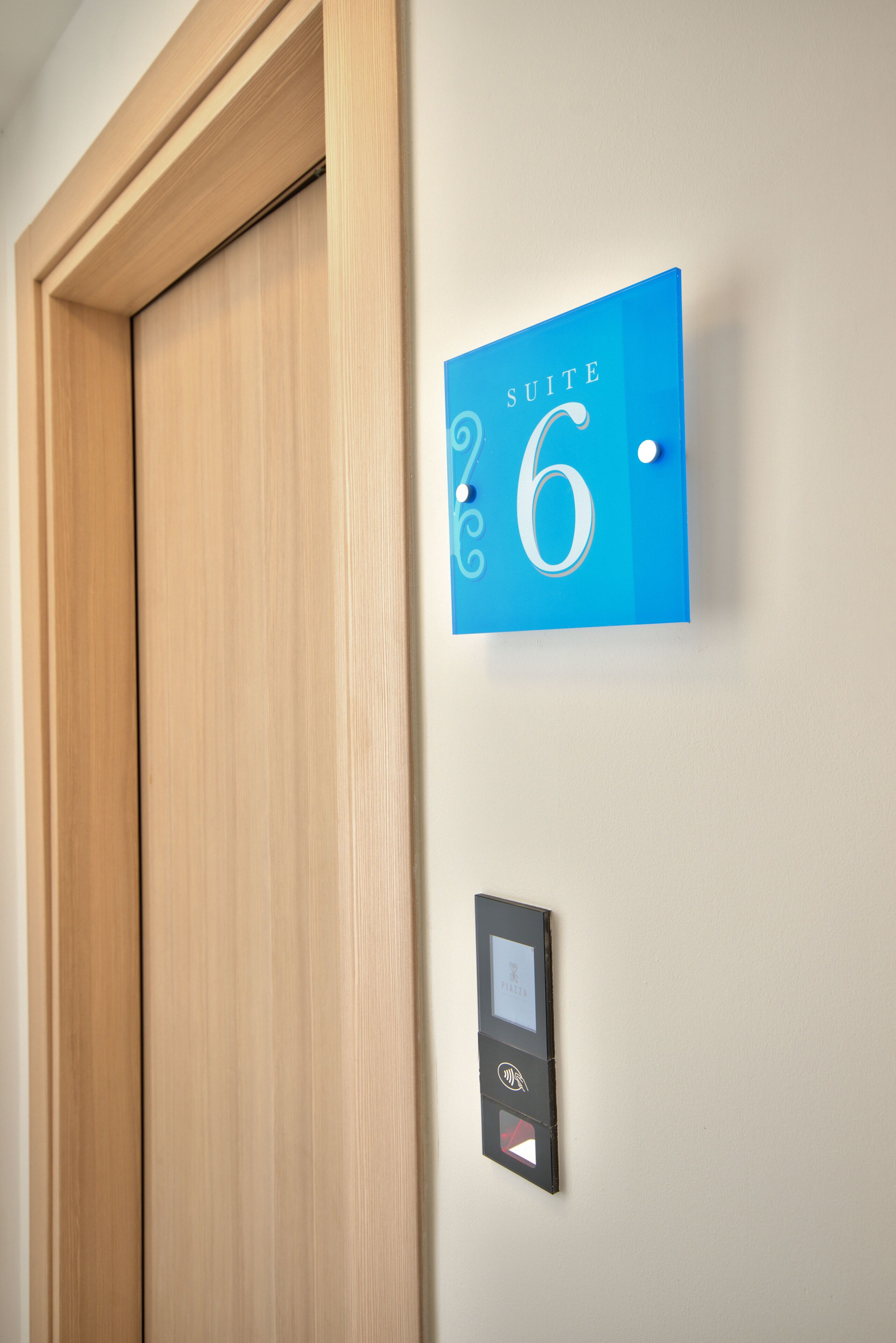 Un panneau bleu portant le numéro 6 et le mot « SUITE », indiquant le numéro d’une chambre d’hôtel.