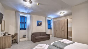 A modern hotel room with two beds, a sofa, a desk, and a wardrobe. - The Suites - Piazza Kirkop (Kirkop)