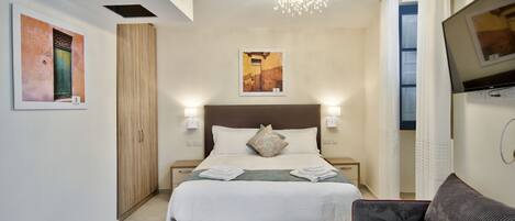 Habitación de hotel con una cama grande, dos mesitas de noche, un televisor y obras de arte en las paredes.
