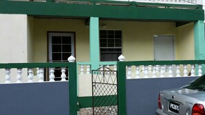 A building with a green and white exterior, a gated entrance, and a parked car.