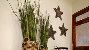 A wooden console table with wicker baskets and a fruit basket, against a wall with decorative star-shaped items and a window. - Hotel Idafe (Las Palmas de Gran Canaria)