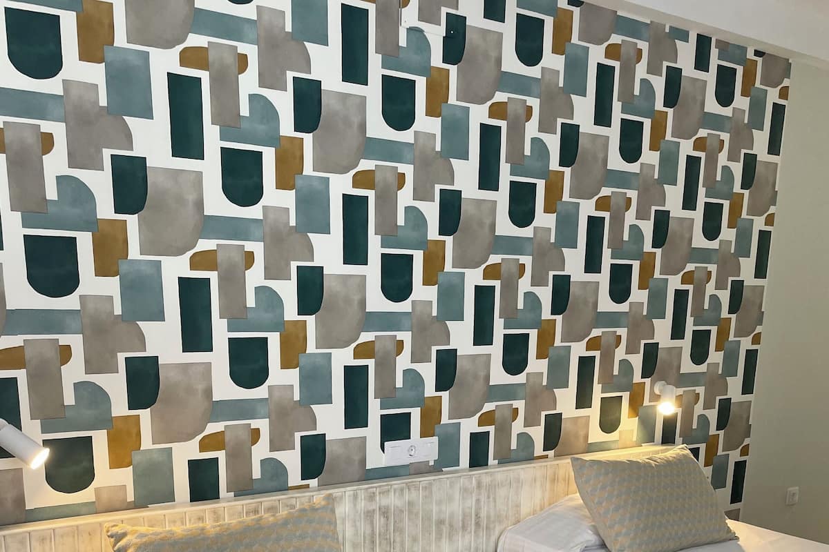 A hotel room with two beds, a patterned bedspread, and a geometric wall design.