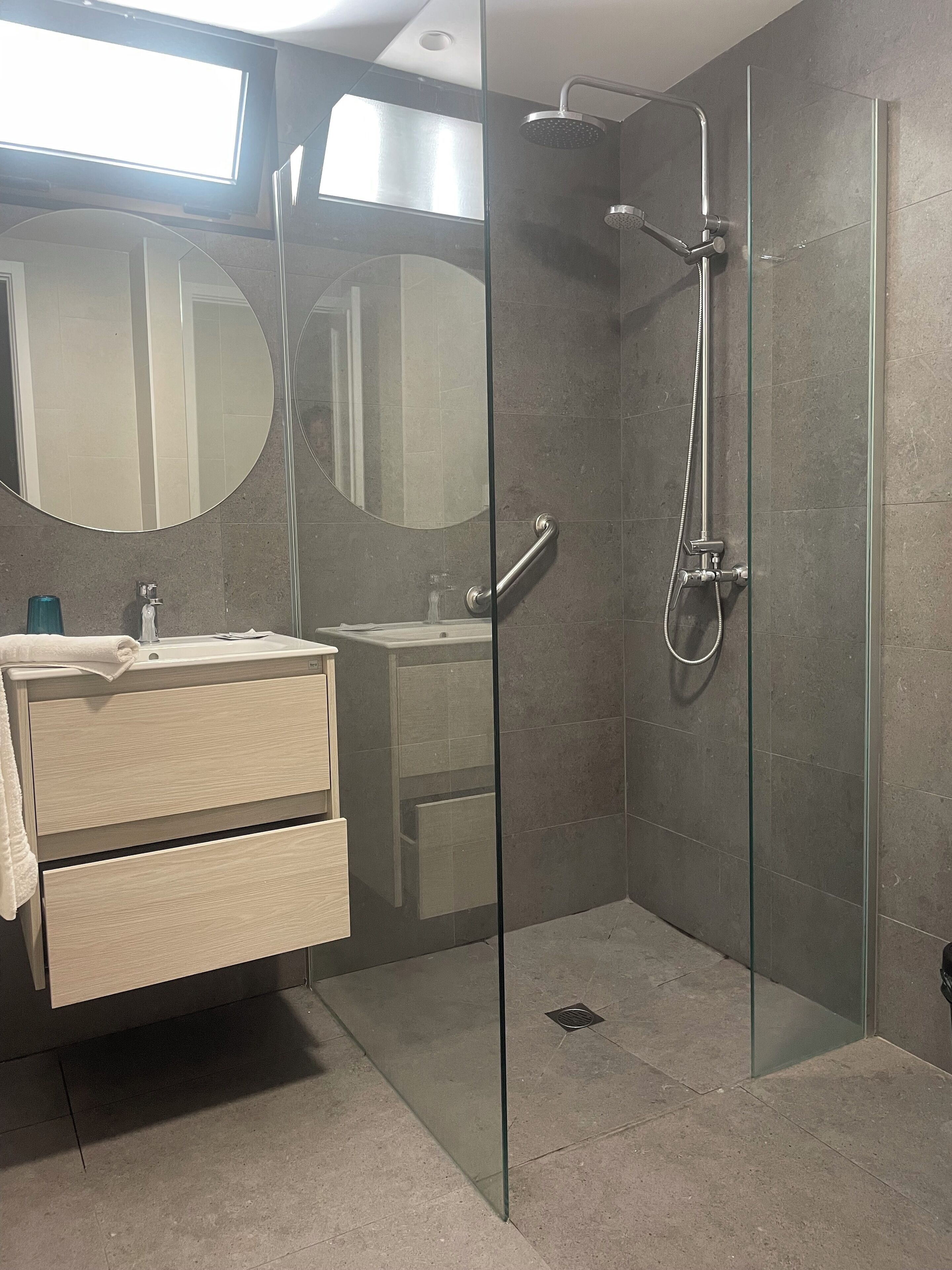 A modern bathroom with a glass shower enclosure, a vanity with a mirror, and a towel on the counter.