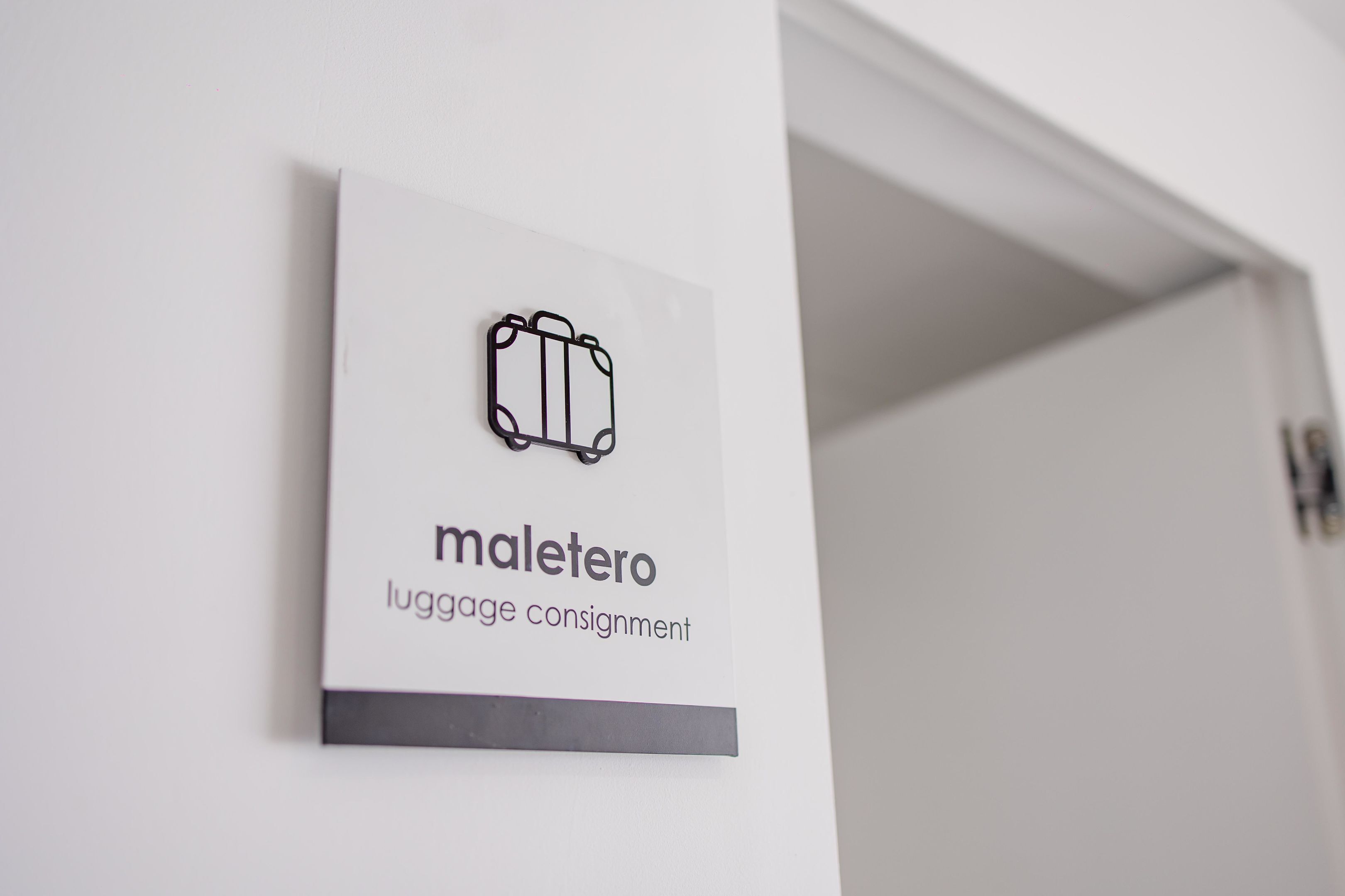 Senyal amb icones de roba de viatge i el text 'maletero luggage consignment'.