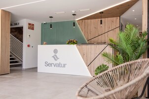 Et moderne receptionsområde med receptionistskranke, træpaneler og trappe.