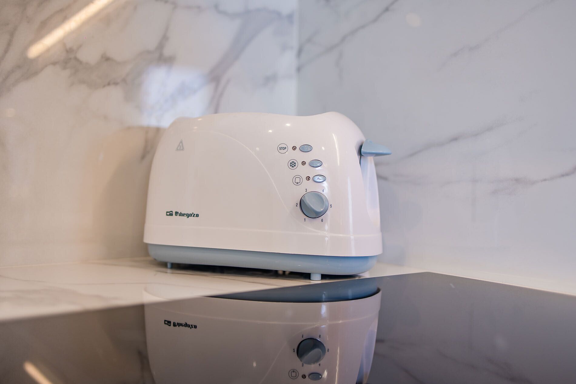 A white and blue toaster with a control panel on a marble countertop.