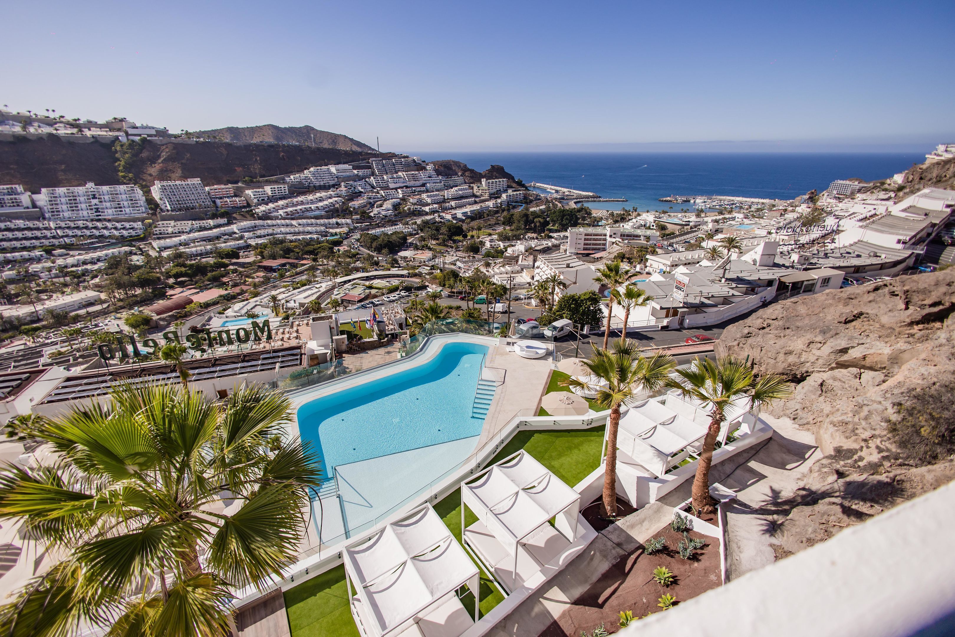 Een resort met een groot zwembad, palmbomen en uitzicht op de oceaan.