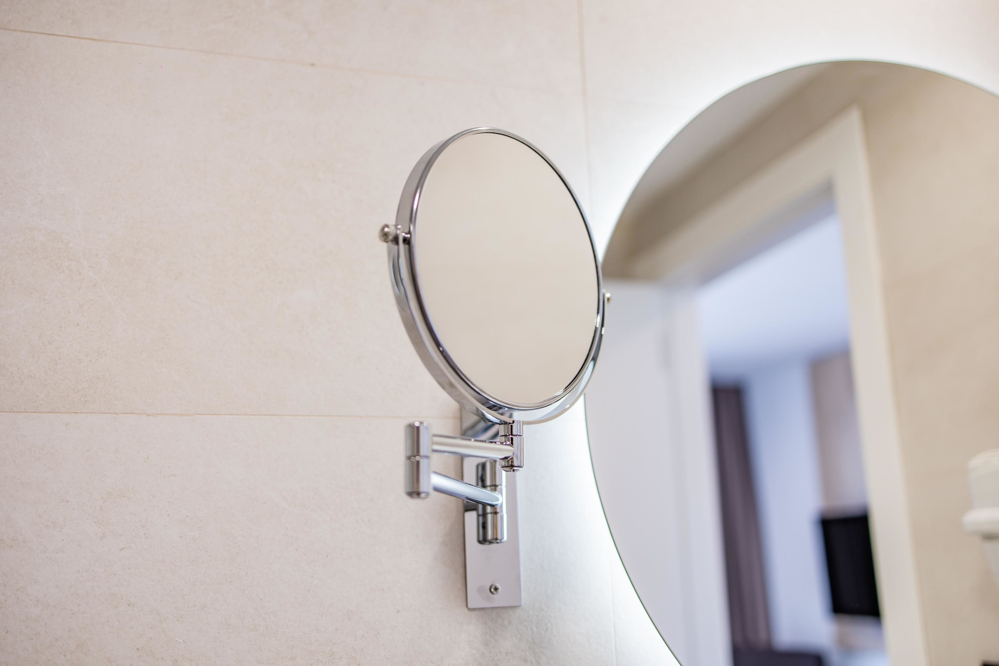 Une salle de bain avec un miroir fixé au mur, des toilettes et un lavabo.