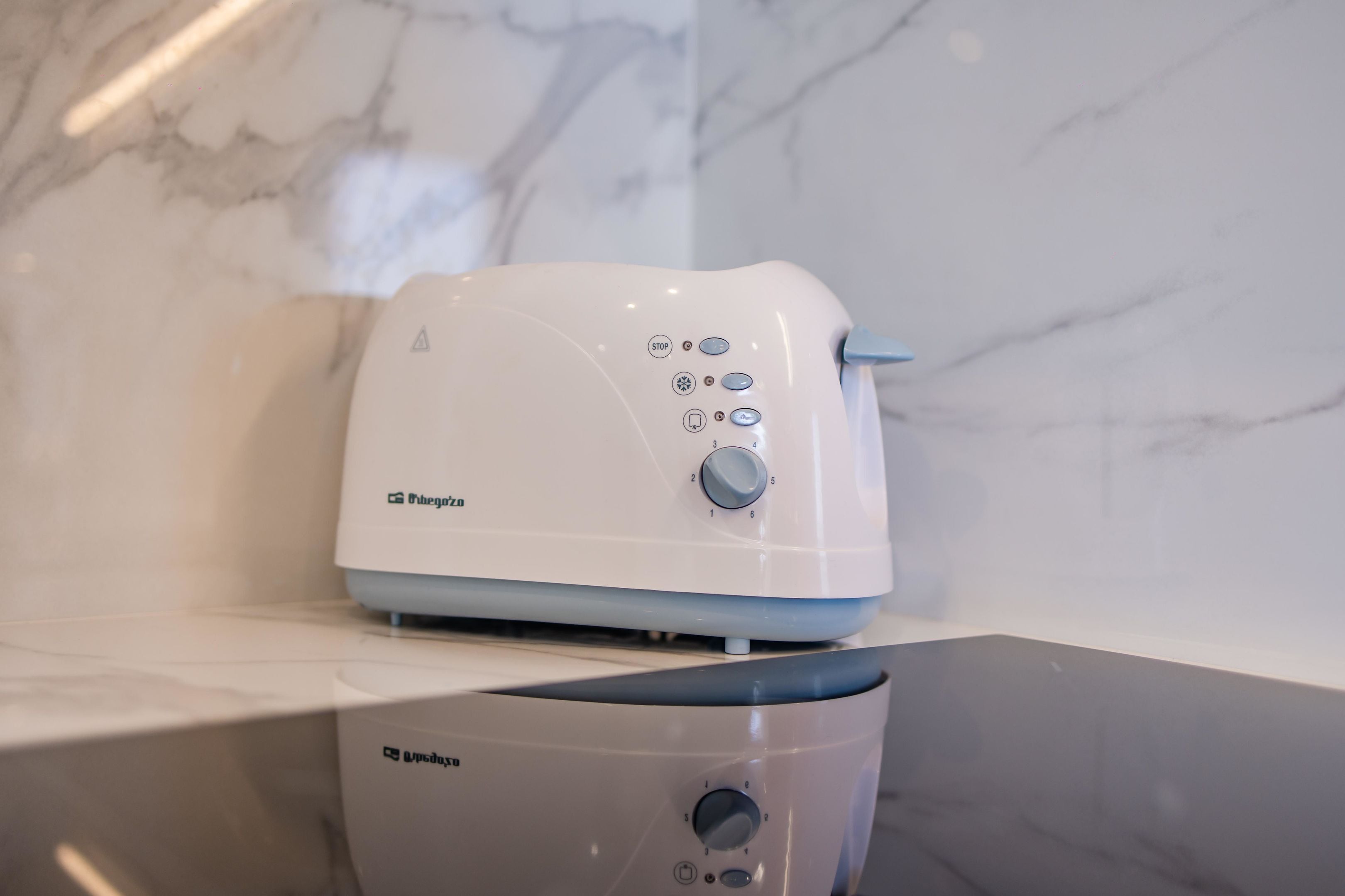 A white toaster with a control panel and a brand logo on a countertop.