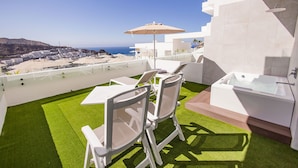 A balcony with a view of the beach, a table with chairs, and a bathtub. - Servatur Hartaguna - Adults Only (Mogan)