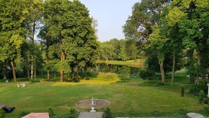 A well-maintained garden with a central pond, surrounded by lush greenery and trees. There are outdoor seating areas with tables and chairs. - Villa am Stechlin (Stechlin)