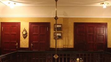 A grand staircase with a wooden railing, a chandelier, and a wall-mounted clock.