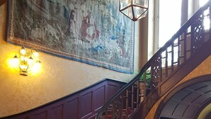 A grand staircase with red carpeted steps leading to a landing with a large ornate chandelier. - Villa am Stechlin (Stechlin)