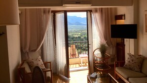 Un salon avec balcon, une télévision à écran plat et une vue sur la campagne.