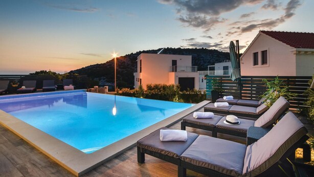 Área de piscina no terraço, com espreguiçadeiras e vista para a paisagem ao redor.