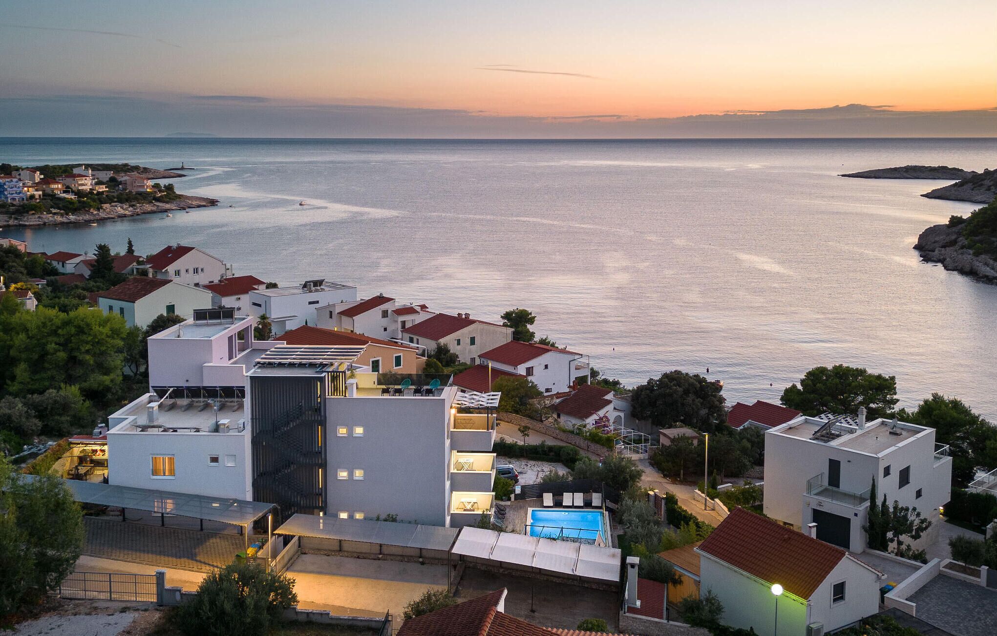 Ein Küstenwohngebiet mit modernen Häusern, einem Swimmingpool und Meerblick.