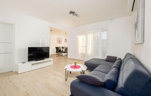 Relax in this stylish living room with a large sofa, flat-screen TV, and dining area.