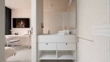 Un baño moderno con tocador blanco, espejo y zona de ducha con azulejos.
