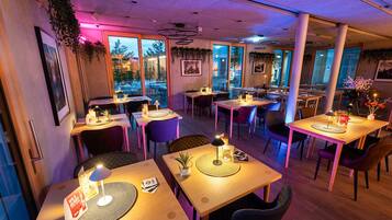 Un restaurante con mesas y sillas de madera y plantas colgantes.
