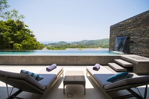 A poolside area with lounge chairs and a stone wall.