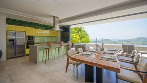 Eine moderne Küche mit einer großen Kochinsel, Barhocker und einem Essbereich mit Tisch und Stühlen.