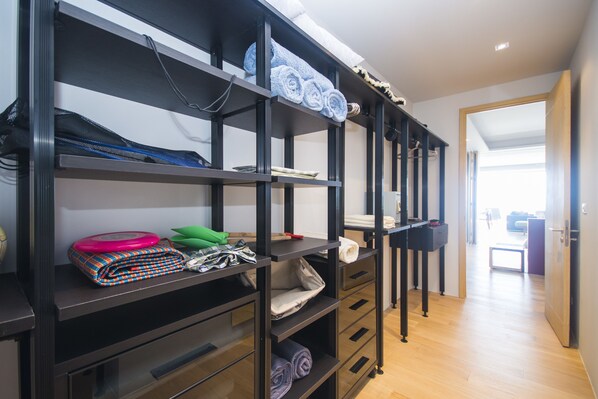 A storage unit with shelves and drawers, containing folded towels, a green bag, and a pink object.